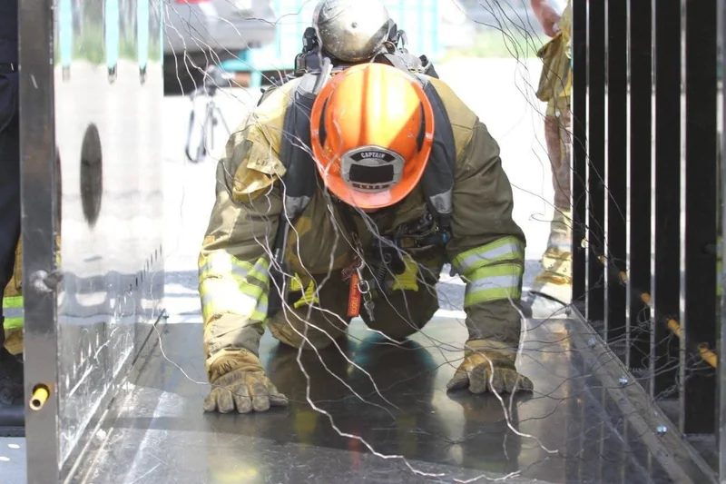 A firefighter moving through a wire-entanglement training prop.